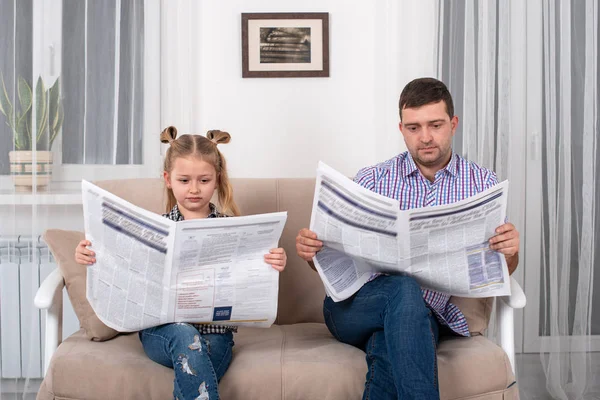 Η μικρή κόρη και ο μπαμπάς κάθονται στον καναπέ στο σπίτι και διαβάζουν — Φωτογραφία Αρχείου