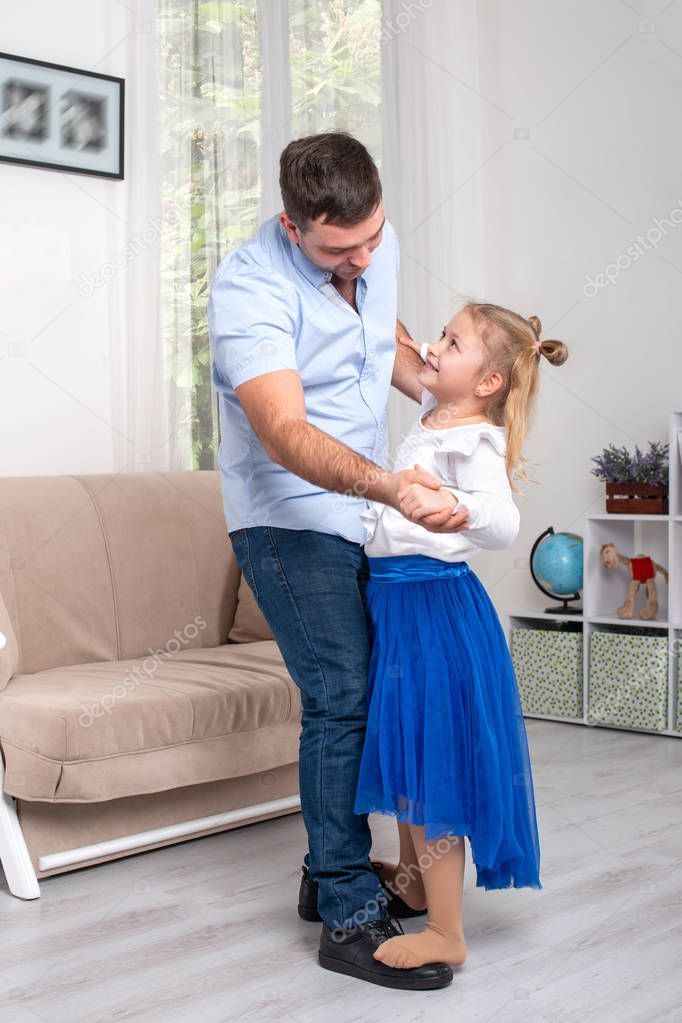 Little daughter and dad dancing with joke  at home 