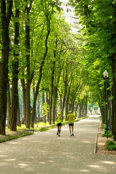 Ein Mann und eine Frau in Sportbekleidung beim morgendlichen Joggen im Park — Stockfoto