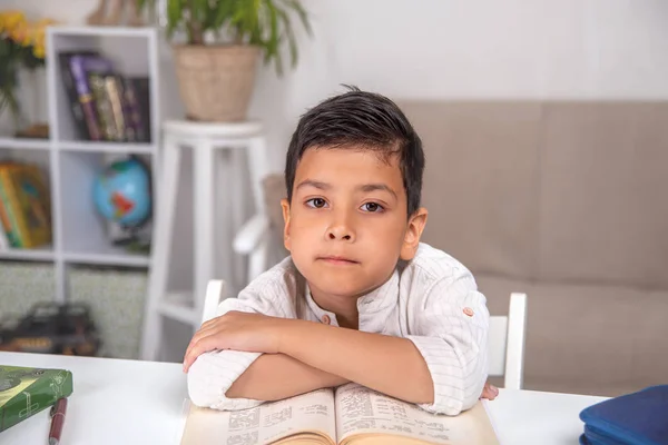 Skolpojken sitter vid bordet hemma och gör sin hemläxa. — Stockfoto