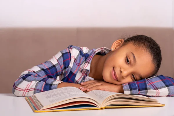 Das Schulmädchen sitzt zu Hause am Tisch und macht seine Hausaufgaben. — Stockfoto