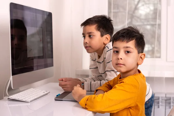 Dos escolares haciendo sus deberes con una computadora. Ellos... — Foto de Stock