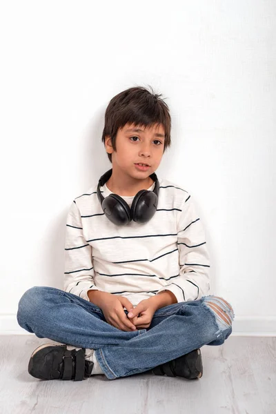 Een jonge jongen het dragen van een wit overhemd en jeans met een koptelefoon — Stockfoto