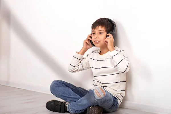 Studio shot van een jonge jongen met een koptelefoon plaatsing op de vloer — Stockfoto