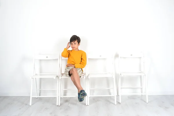 Un garçon est assis seul sur une chaise dans une salle d'attente et parle — Photo