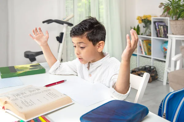 Skolpojken sitter vid bordet hemma och gör sin hemläxa. — Stockfoto