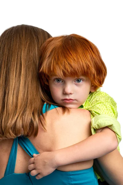 Waist up portrait of a little redhead boy gently hugging his mom Stock Image