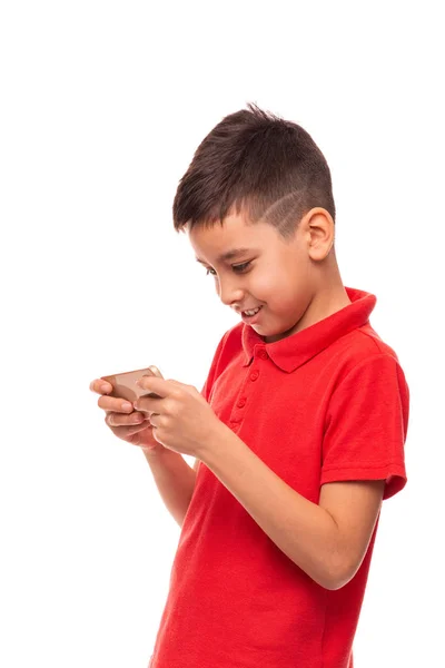 Молодой улыбчивый мальчик пишет или читает SMS или играет в игры на — стоковое фото