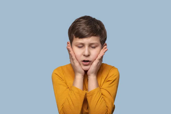Een jonge jongen in wanhoop sluiten zijn ogen dicht zijn wangen met — Stockfoto