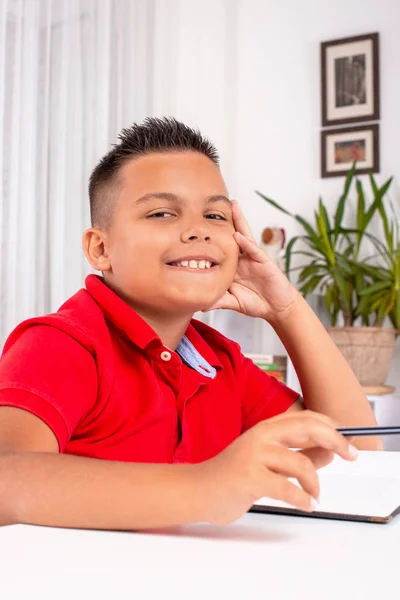 Portret van de school jongen aan tafel binnen en — Stockfoto