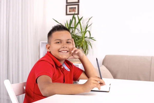 Portret van de school jongen aan tafel binnen en — Stockfoto