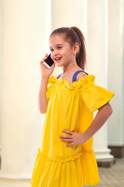 Portret van een glimlachend meisje met lang haar praten op de telefoon. — Stockfoto