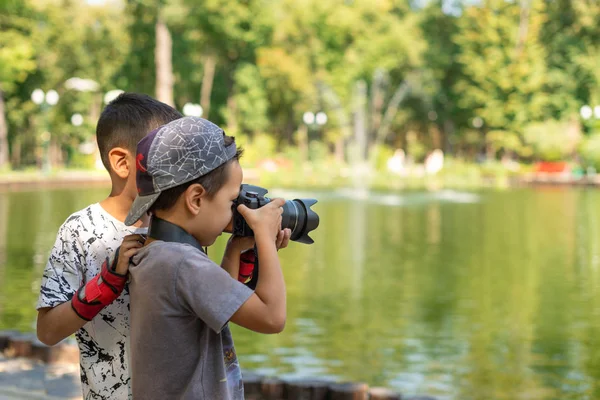 Двое мальчишек стоят у озера и фотографируют природу в лесу. — стоковое фото