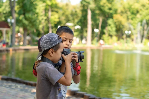 Двое мальчишек стоят у озера и фотографируют природу в лесу. — стоковое фото