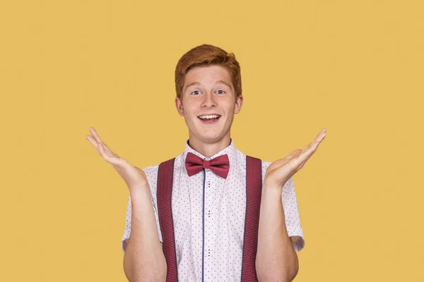 Shot of a cheerful young man with gesturing hands against  yello — Stock Photo, Image