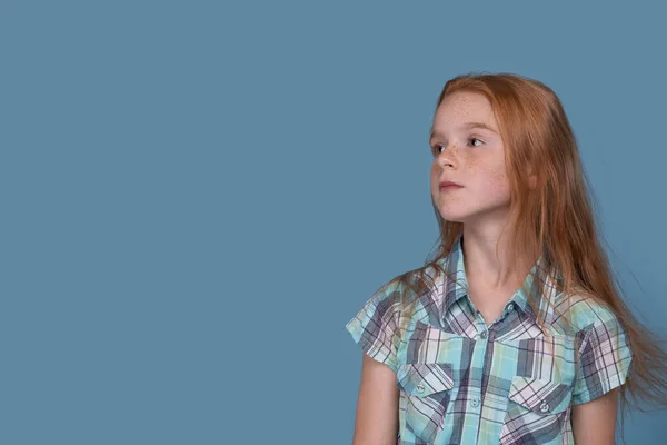 Une jeune fille attrayante avec des cheveux roux et des taches de rousseur contre blu — Photo