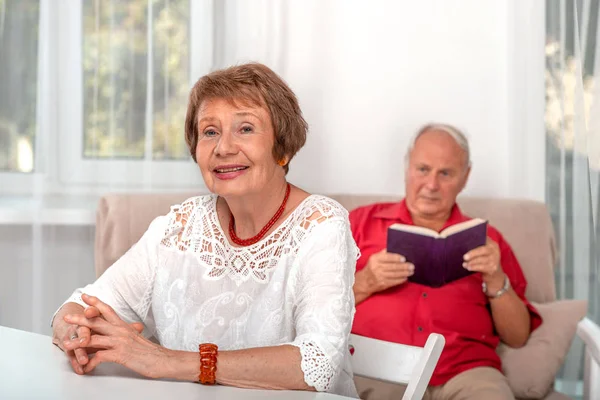 Taillenporträt einer lächelnden Seniorin, die an einem Tisch in — Stockfoto