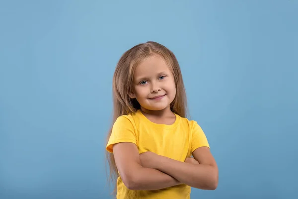 Een lachend klein meisje met lang blond haar en blauwe ogen tegen — Stockfoto