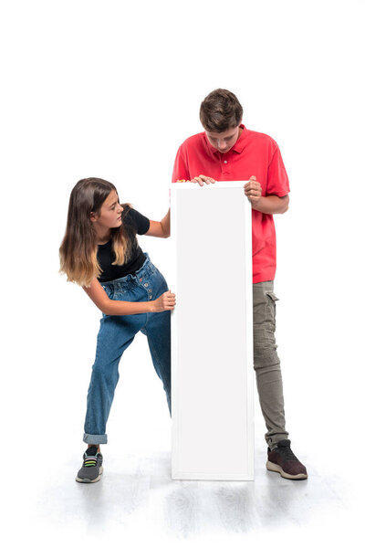 Studio shot of   young boy and girl holding white billboard with copy space against white background