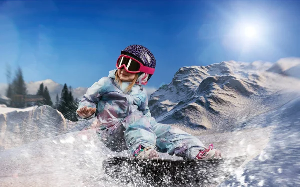 Little snowboarder girl riding snowboard in the mountains Royalty Free Stock Images
