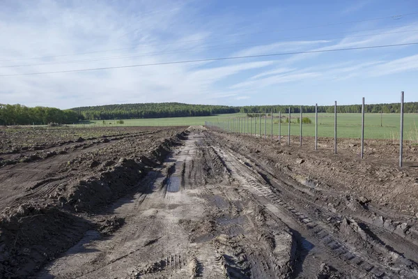 Agricultural field, which is fenced and between there is a field road
