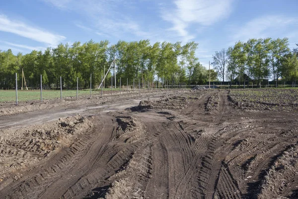 Campo agrícola, que é cercado e entre há uma estrada de campo — Fotografia de Stock