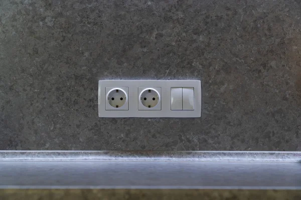Two Power sockets and light switch in frame on texture wall as a background and kitchen countertop — ストック写真