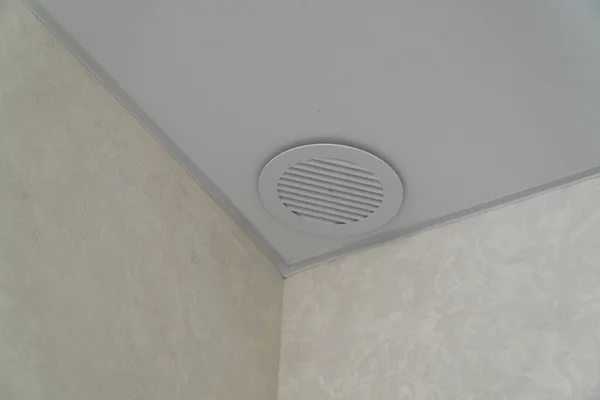 Round air-conditioning outlet on white ceiling