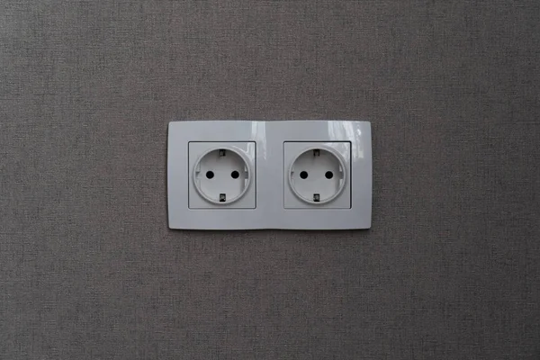Dos tomas de corriente blancas con marco en la pared gris oscuro como fondo —  Fotos de Stock