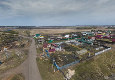 Kolyutkino köyünde evler ve alanlar. Hava, yay, bulutlu