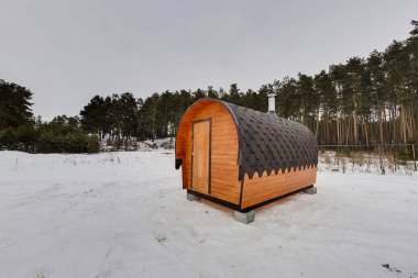 Ahşap varil şeklinde mobil banyo. Arka plan olarak orman