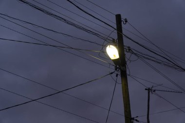 Eski elektrik direği, tel, lamba (lamba üzerinde) ve cloundy mavi gökyüzü arka plan ile diğer şeyler Coseup.