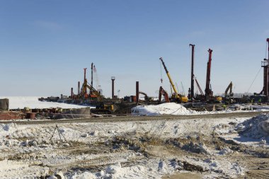 Sondaj ekipmanları, ekskavatörler, kamyonlar Sabetta deniz limanı inşa. Yamal, Rusya. Kış, güneşli