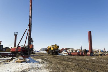 Sondaj ekipmanları, ekskavatörler, kamyonlar Sabetta deniz limanı inşa. Yamal, Rusya. Kış, güneşli