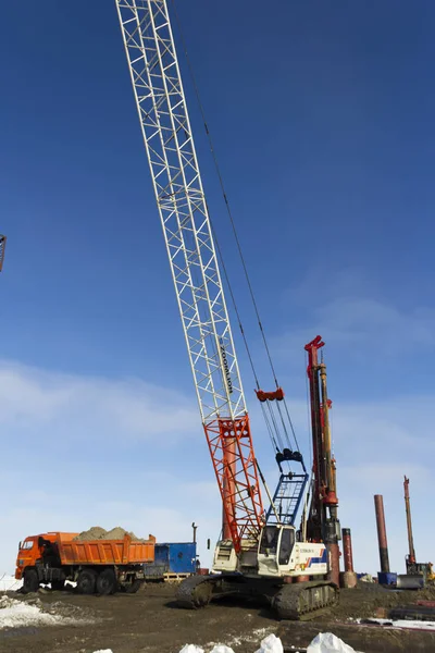 Sprzęt wiertniczy, koparki, ciężarówki i żurawie budowlane budować port morski Sabetta. Yamal, Rosja. Zima, słonecznie — Zdjęcie stockowe