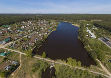Kamenka köyünde bir gölet, bir baraj ve yol. Güneşli, yaz, Hava