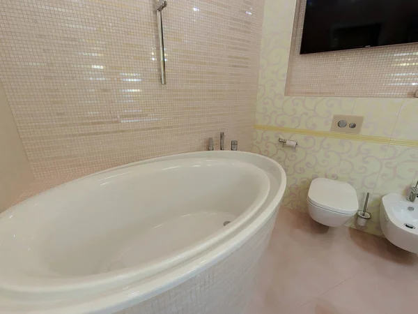 Ekaterinburg, Rusia. Octubre 01, 2014. Aseo de lujo interior y baño con luz cálida. Bañera, WC, bidet, tv — Foto de Stock