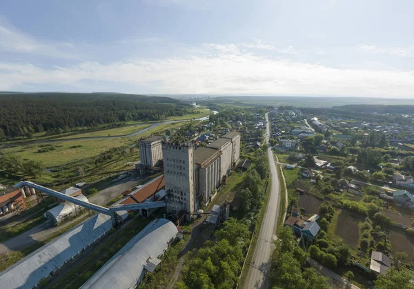 Elevator of flour mill and Iset river in Aramil village. Aerial, summer, sunny