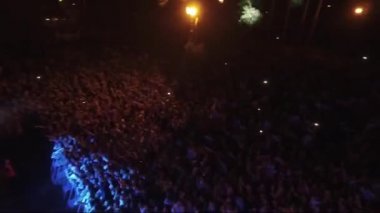 Festivalin hava manzaralı kalabalığı ellerini kaldırıyor. Ormanda gece açık hava konseri. Festival kalabalığı ellerini kaldırıyor.