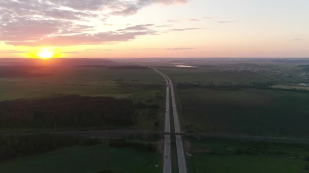 夕暮れ時の高速道路やフィールドの空中ビュー 高速道路の鉄道橋の上 車は高速道路を走る 太陽は地平線上に沈む ロシア エカテリンブルク市の近くのチェリャビンスク高速道路 — ストック動画
