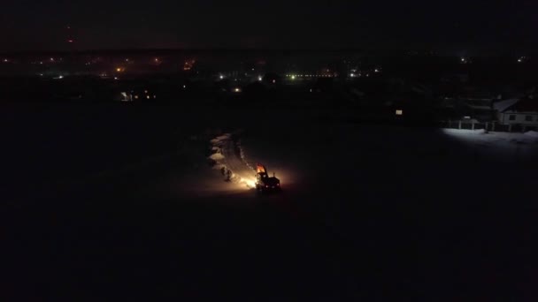 Luchtfoto Van Graafmachine Rijdt Nachts Een Wintersneeuwveld Rijden Het Dorp — Stockvideo