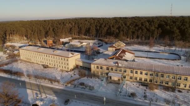 村の学校の空中ビュー 学校のホッケーコートや森の後ろに 外は雪が降っている ロシア スヴェルドロフスク地方 オクタイブラスキー州 — ストック動画