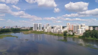 Şehirdeki nehir kıyısındaki modern çok katlı evlerin havadan görünüşü. Kamera yükselir ve şehrin panoramik bir görüntüsünü sunar. Güneşli bir yaz günü. Rusya, Ekaterinburg