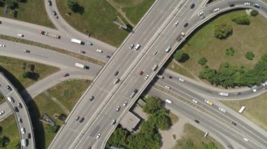 Otobanın yukarıdan aşağıya bakan manzarası. Şehirdeki araba trafiğiyle kavşak. Yeşil ağaçların ve çimlerin ortasındaki otoban. Yaz güneşli bir gün