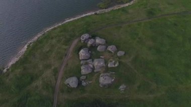 Uçsuz bucaksız bir arazide devasa taşların (kayaların) havadan görünüşü. Yakınlarda toprak bir yol var. Mavi gökyüzündeki bulutlar. Yaz güneşli bir gün