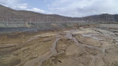 Kuru nehir yatağının hava manzarası Karabash şehrindeki bakır üretimiyle zehirlendi. Yolun kenarına. Arabalar yol boyunca sürüyorlar. Bahar bulutlu bir gün. Rusya, Chelyabinsk bölgesi