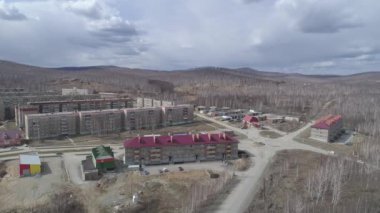 Karabash şehrinin üç katlı ve beş katlı evleri var. Bahar, yapraksız ağaçlar. Arka planda Ural Dağları. Rusya, Chelyabinsk bölgesi