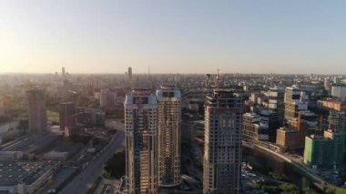 Şehirdeki çok katlı binaların hava manzarası. Bazı evler inşa edildi, bir ev hala yapım aşamasında. Çatılarda helikopter pistleri de var. Arabalar yolda gider..