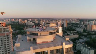 Parti ve insanlar Gökdelen 'in çatısında. Akşam şehrindeki gökdelenlerin hava görüntülerine göre gün batımında önemli bir yerleşim bölgesinde. Arka planda modern şehir. Arabalar yolda gider..