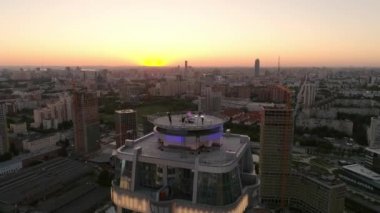 Parti 'nin gökdelenin çatısındaki hava görüntüsü. Akşam sıcak yaz şehri gün batımında. İnşaat alanı, binalar ve kule vinçlerinin yanında.